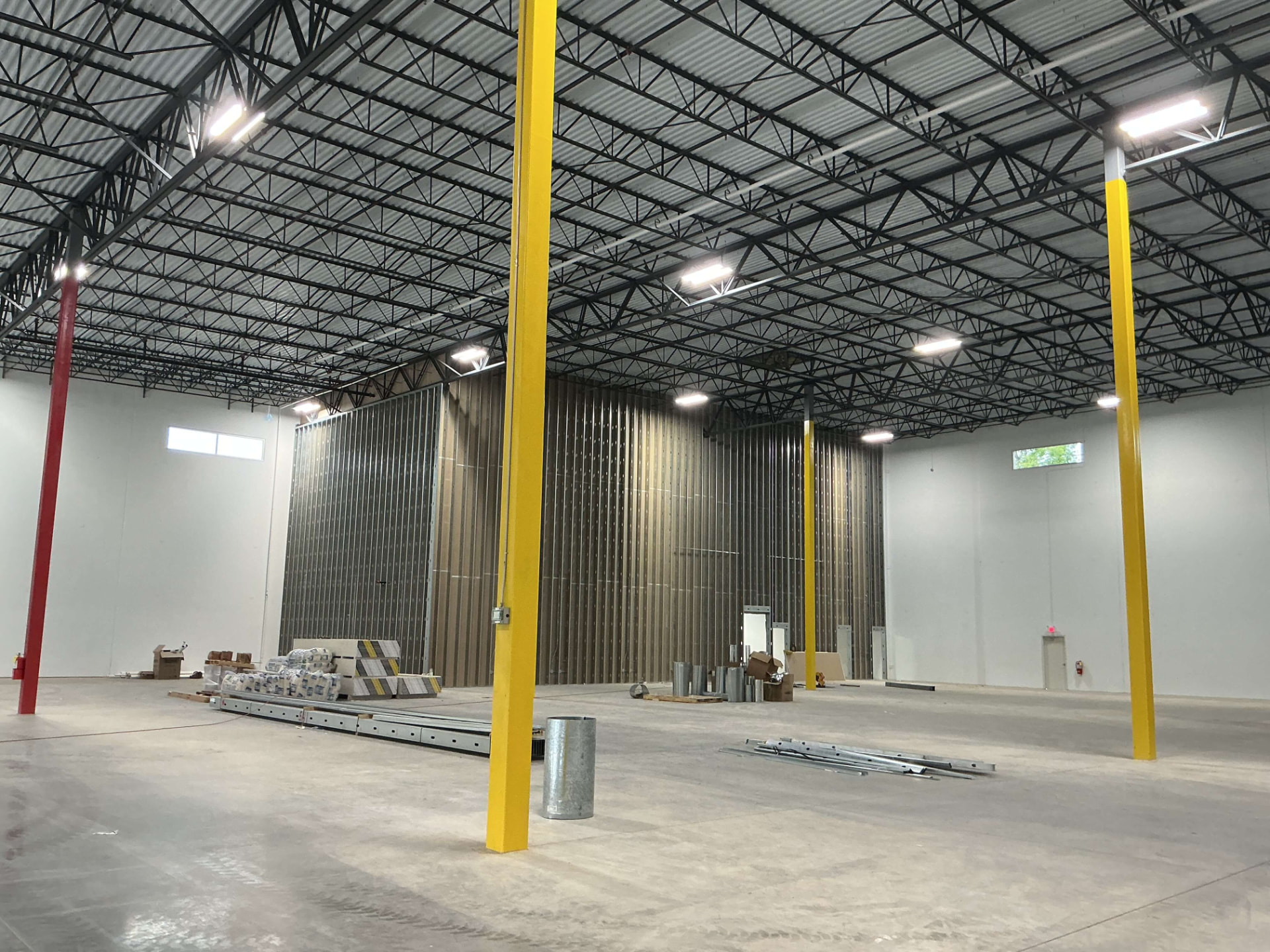 Interior metal stud framing on tall commercial walls beside painted drywall